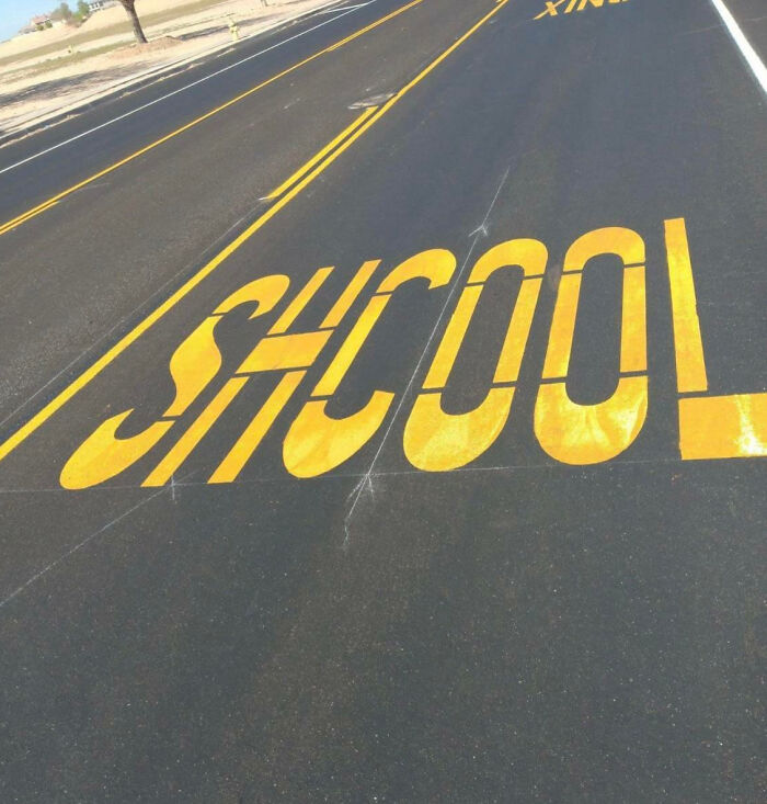Road marking with the word school painted incorrectly, showing a funny example of people not even trying.