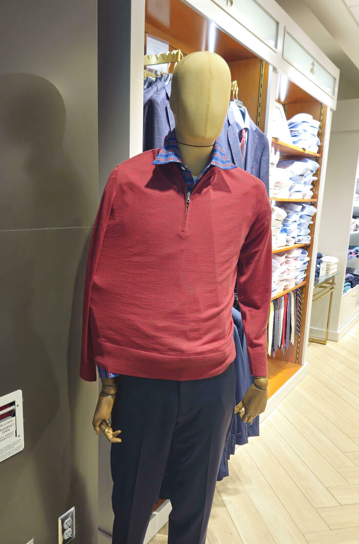 Mannequin dressed in a red sweater and blue pants with one arm missing, a funny example of people not even trying.