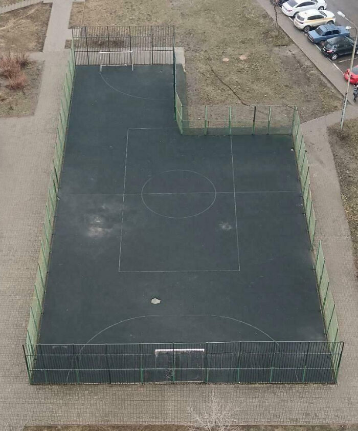 Outdoor soccer field with incomplete fencing and a missing section, showcasing people not even trying to finish the job.
