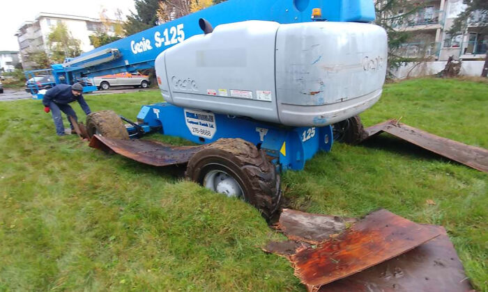 Man struggling to move equipment stuck in the mud, illustrating funny examples of people not even trying at work.