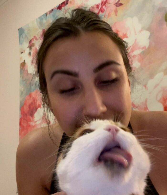 Woman holding a cat close while the cat makes a funny face, showcasing animals who can take better selfies.