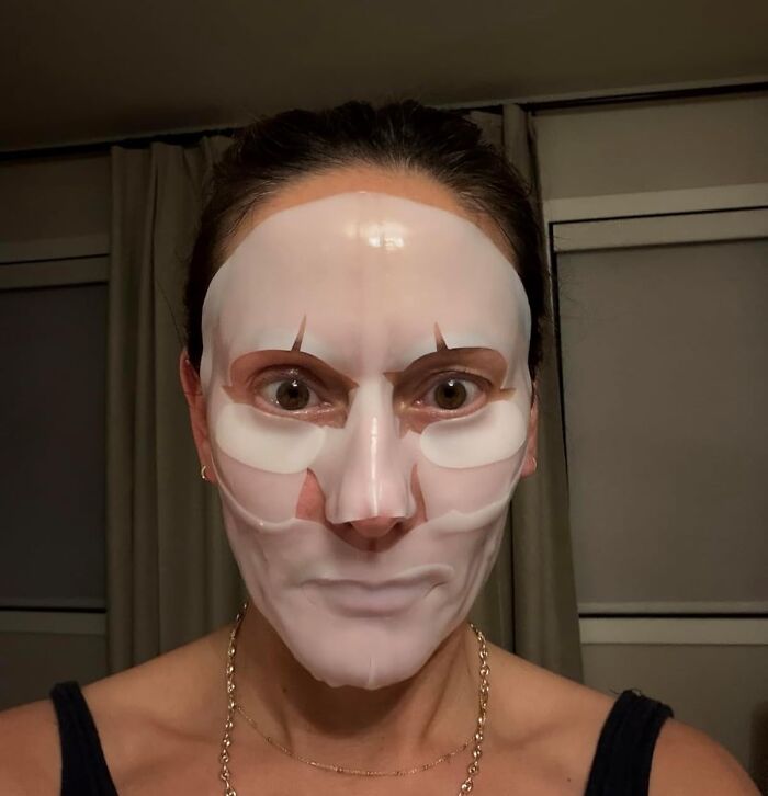 Woman wearing a white facial sheet mask indoors, illustrating self-care gifts for holiday shopping satisfaction ideas.