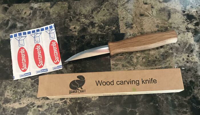 Wood carving knife with a wooden handle on a marble surface, showcasing practical smart ideas and inventions solving problems.
