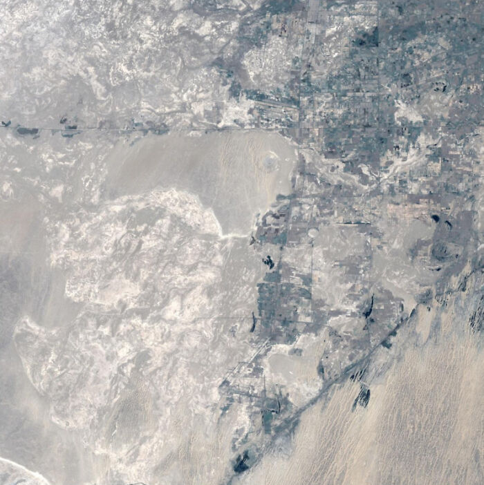 Aerial view showing a desert landscape with mixed terrain and scattered agricultural plots for where was this taken posts.