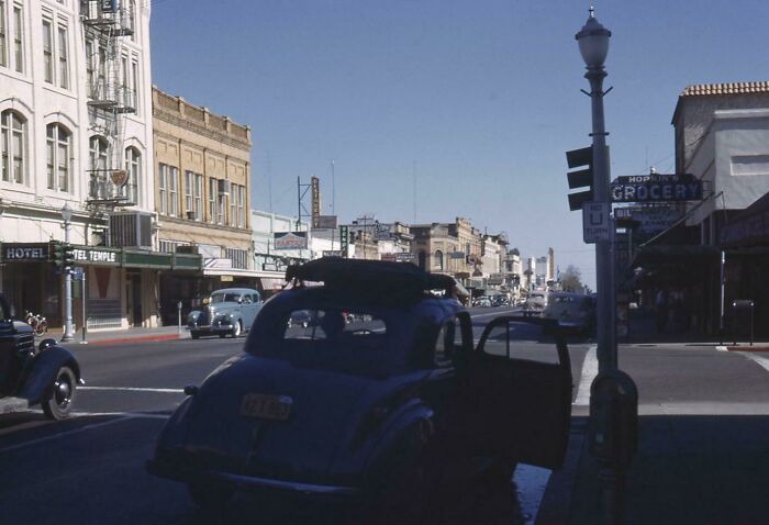Vintage cars parked on a quiet downtown street with old buildings in a classic where was this taken post.