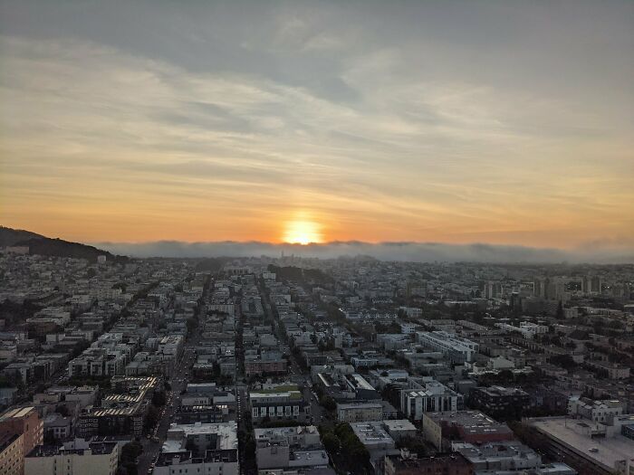Cityscape at sunset with sun setting behind clouds, illustrating where was this taken posts trending online.