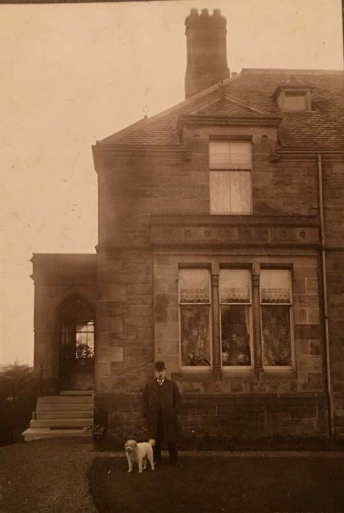 Vintage photo of a man with a dog standing outside a stone house, illustrating where was this taken internet posts.