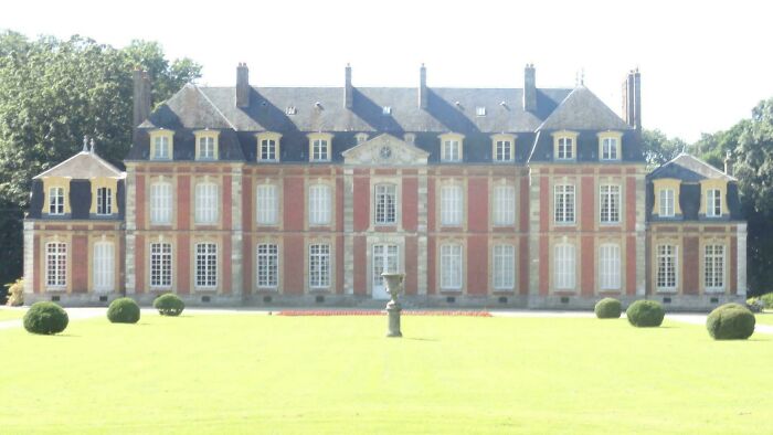 Large historic chateau with manicured lawn and bushes, featured in popular where was this taken posts online.