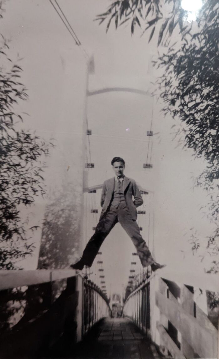 Man in vintage suit balancing legs apart on bridge railing in black and white photo for where was this taken internet posts