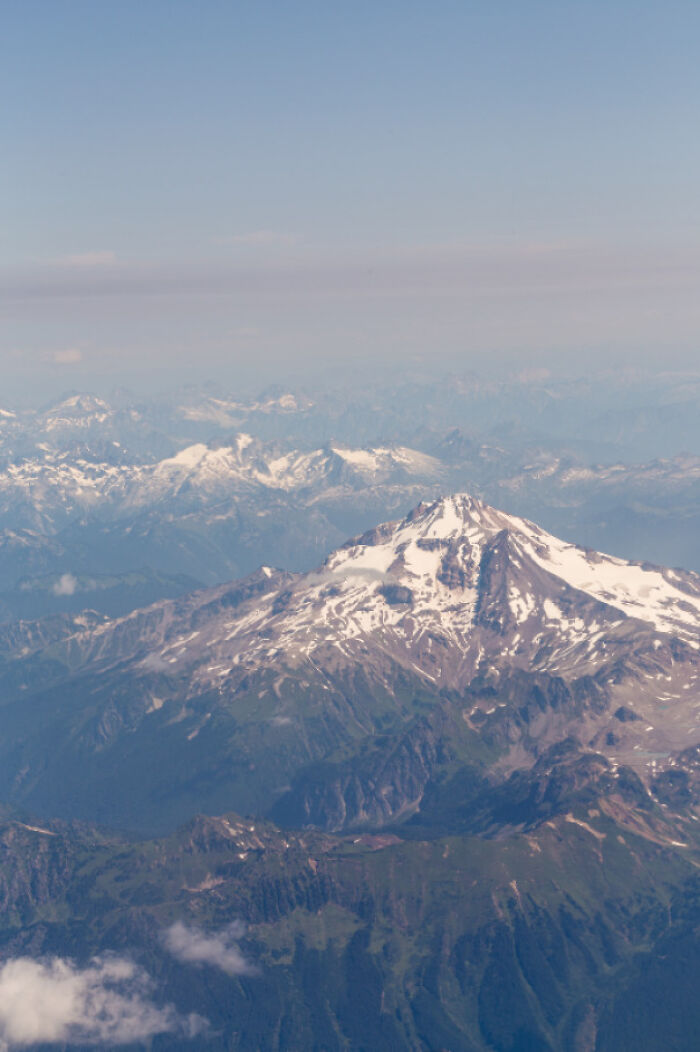 Aerial view of snow-capped mountains with green valleys under a clear sky for where was this taken posts.