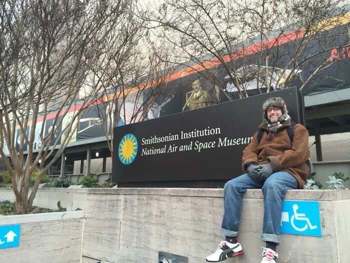 Man sitting outside Smithsonian National Air and Space Museum, celebrating big and small dreams turned into reality.