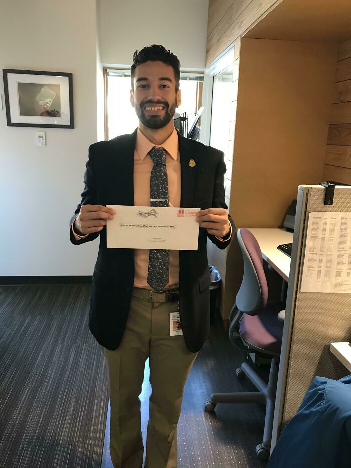 Man in office attire smiling and holding envelope, celebrating turning big and small dreams into reality.
