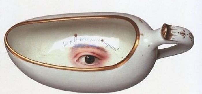 Very old ceramic object shaped like an eye cup with an painted human eye inside, showing ancient craftsmanship.