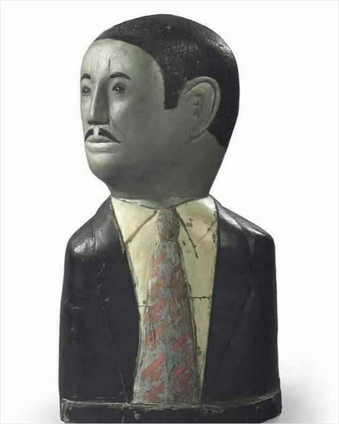 Wooden sculpture of a man in a suit and tie, an example of very old objects that tell stories about ancestors.