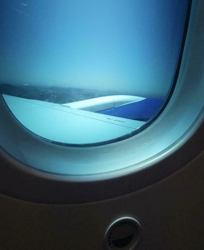 View from airplane window showing wing and clear blue sky, illustrating smart ideas and inventions in aviation design.