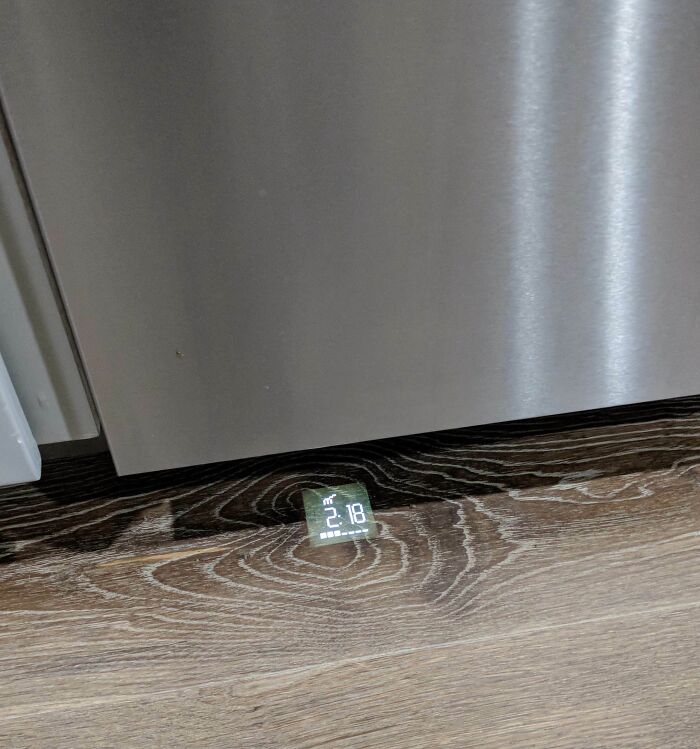 Projection of time and status on the floor below a stainless steel appliance, showcasing a smart invention solving everyday problems.