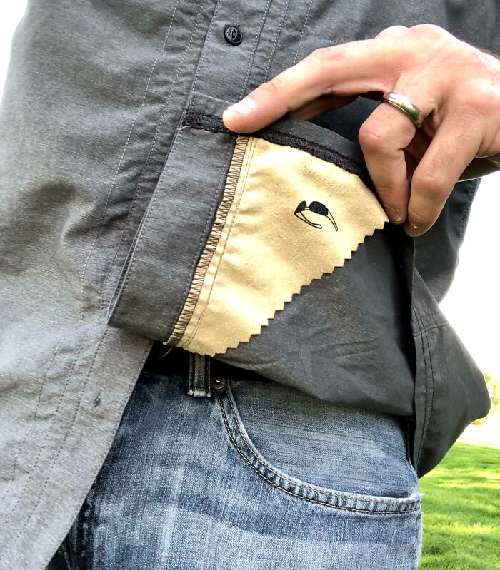 Hand holding a built-in microfiber cloth inside a shirt pocket, one of the smart ideas and inventions solving a problem.
