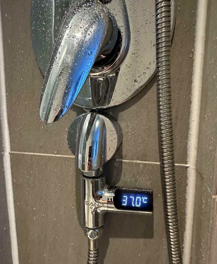 Digital shower temperature display on chrome faucet showing 37 degrees Celsius as a smart idea invention solving water temperature control.