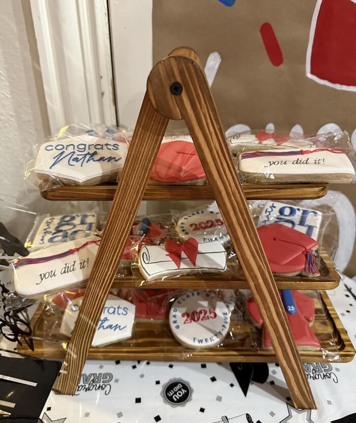Graduation-themed cookies displayed on a wooden stand, featuring congratulatory messages and 2025 graduation designs.