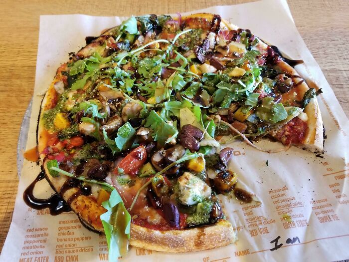 Vegetarian pizza with fresh greens, balsamic glaze, and colorful vegetables, highlighting juicy and buttery dish complaints.