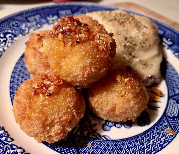 Golden crispy fried balls with a creamy side on a blue patterned plate showcasing juicy steak and buttery lobster flavors