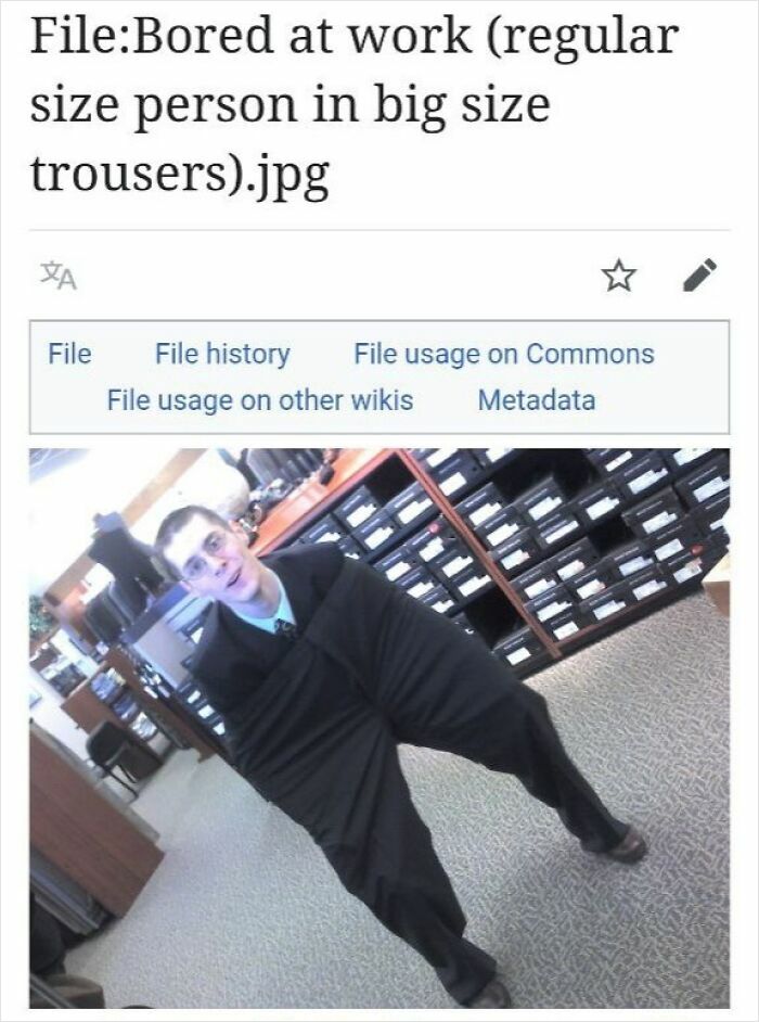Person wearing oversized trousers in an office setting, a humorous moment from funny Wikipedia pages shared online.