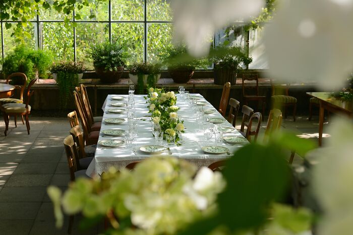 Wedding table set with white linens and floral centerpieces in a sunlit room, highlighting wedding and community event themes.