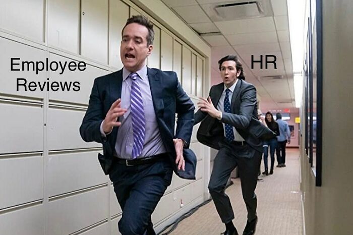 Man labeled HR in a suit chasing another man labeled Employee Reviews in an office hallway, illustrating HR chaos memes.
