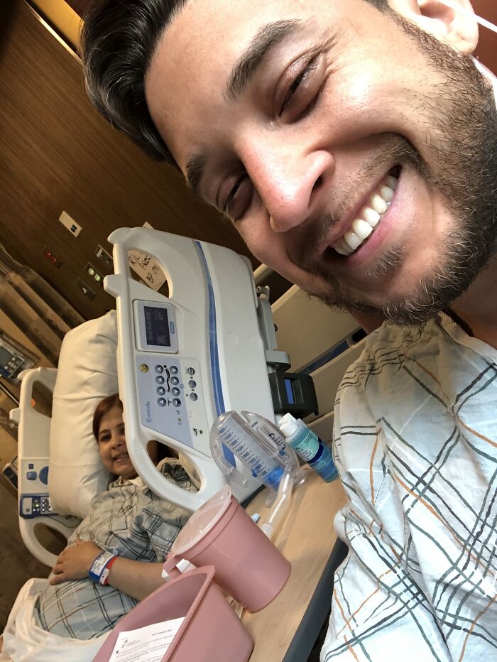 Smiling man visiting his sibling in a hospital bed, showing gratefulness and sibling support during a hospital stay.