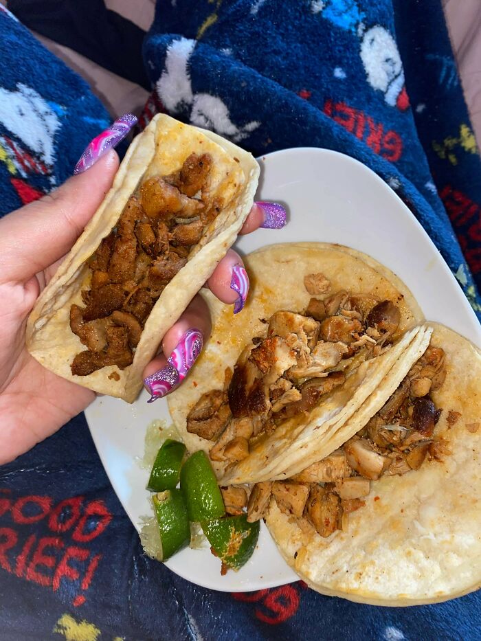 Close-up of seasoned meat tacos on a white plate with lime wedges, highlighting juicy steak and buttery lobster flavors.