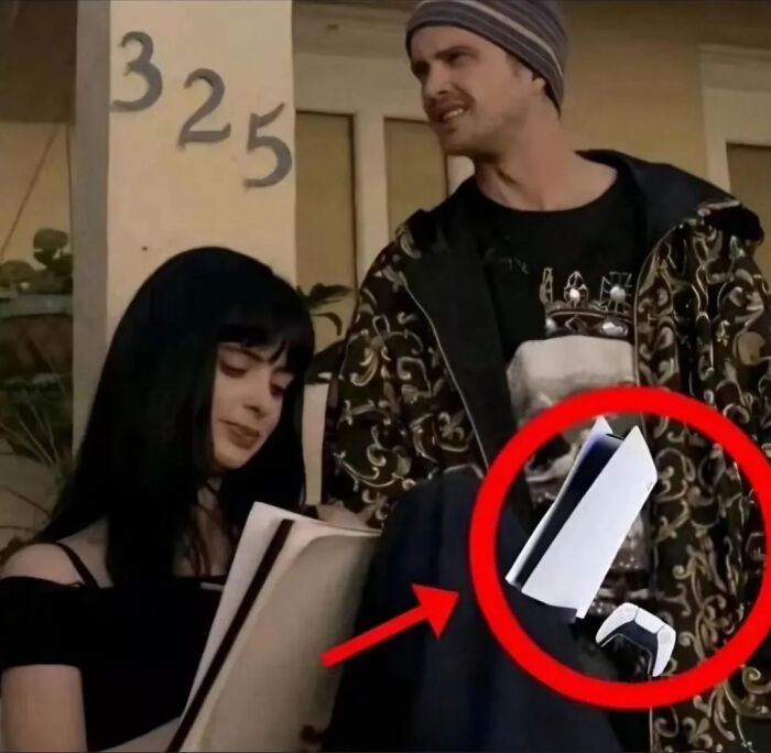 Two people standing near a building with a light fixture that looks like a video game console controller.