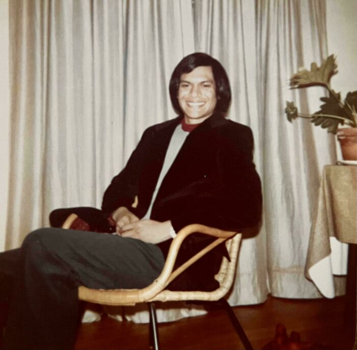 Person smiling while sitting on a chair indoors, representing people turning their dreams into reality and inspiring the internet.
