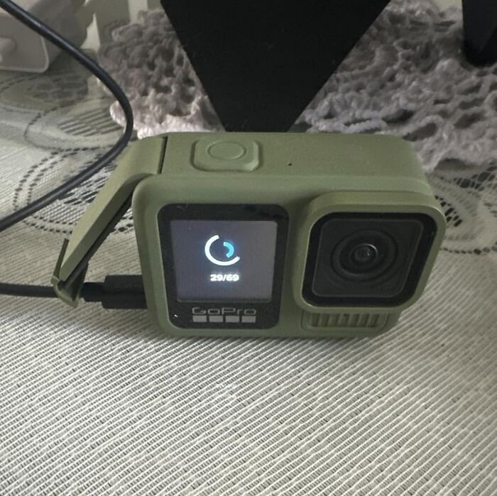 GoPro action camera in green housing charging on a table, illustrating Black Friday week hot deals for tech gadgets.