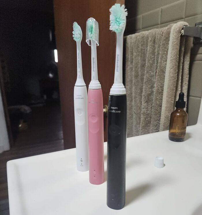 Three electric toothbrushes in white, pink, and black on a bathroom counter, highlighting Black Friday Week deals.