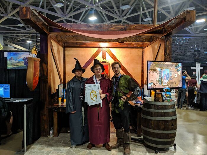Three people in fantasy costumes at a convention booth, showcasing creative projects that inspire big and small dreams online.