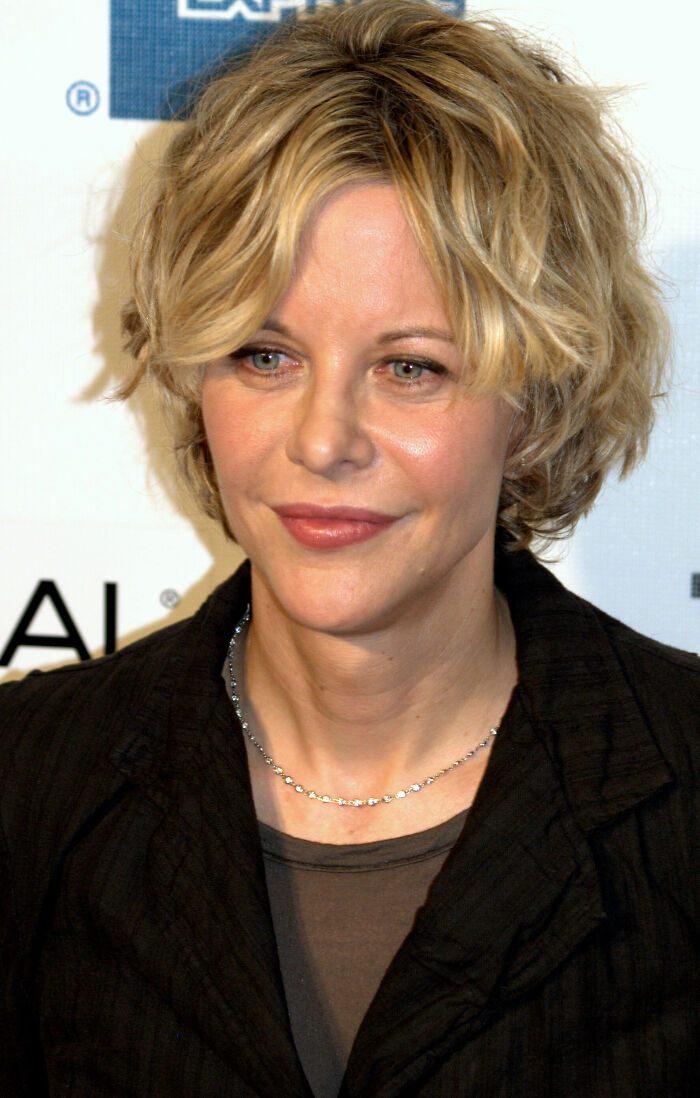 Meg Ryan with short blonde hair and a black jacket at a media event, highlighting her bio and career.