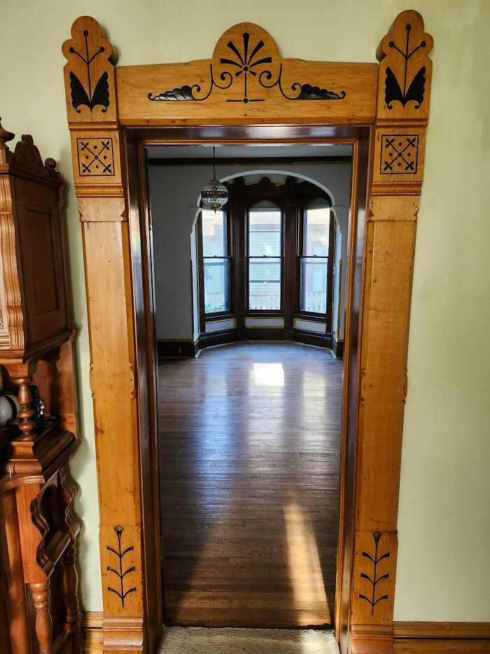 Ornate wooden doorway showcasing craftsmanship in a beautiful old house with hardwood floors and bay windows.