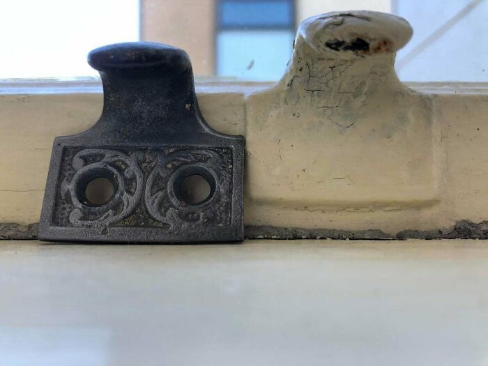 Close-up of detailed old house window latch showing craftsmanship in vintage architecture and building materials.