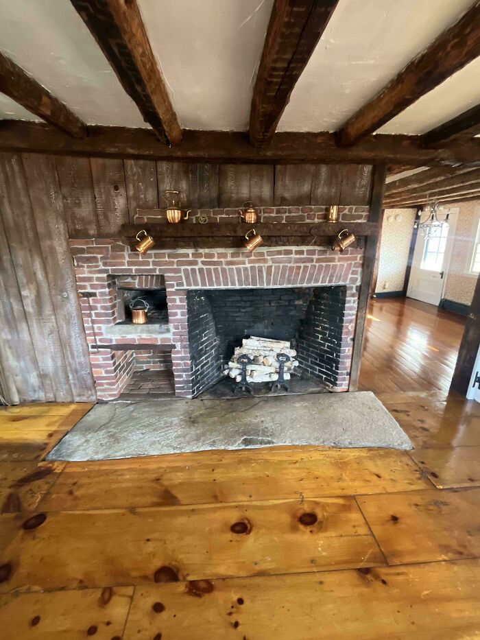 Rustic brick fireplace and wooden beams in a beautiful old house showcasing craftsmanship that has stood the test of time.