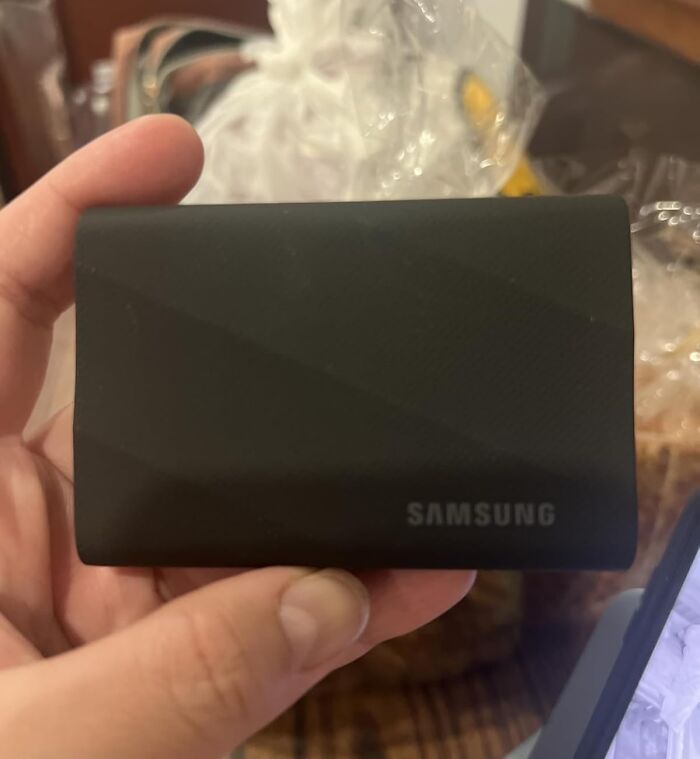 Hand holding a black Samsung portable external hard drive, a popular main character splurge of Black Friday week.