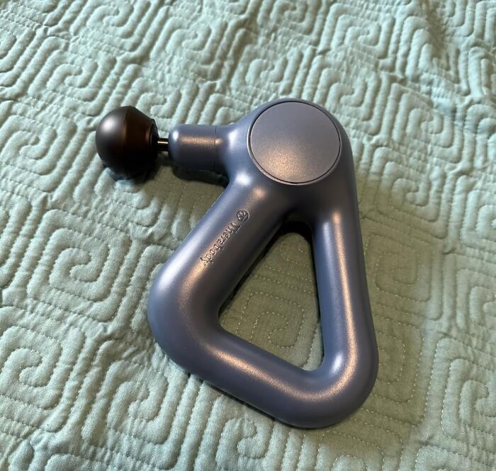 Percussion massage gun on a textured fabric surface, highlighting main character splurges of Black Friday week.
