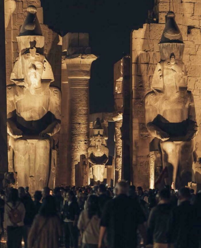 Large ancient statues illuminated at night with crowds of people, showcasing fascinating archeology finds from around the world.