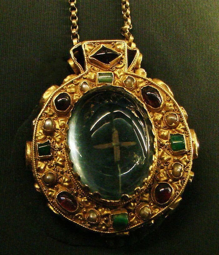 Ornate ancient gold pendant with gemstones and a large central polished stone, a fascinating archeology find from around the world.