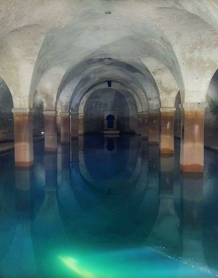 Ancient underground archaeological site with stone arches and reflective water pool showcasing fascinating archeology finds.