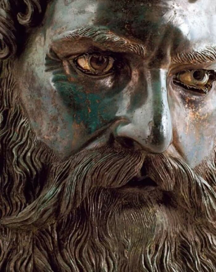 Close-up of an ancient bronze sculpture showing detailed facial features and beard from a fascinating archeology find.