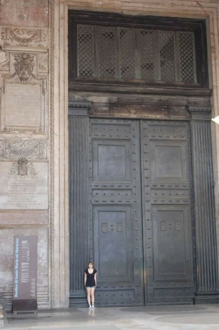 Woman standing by massive ancient door in historical site, showcasing fascinating archeology finds from around the world.