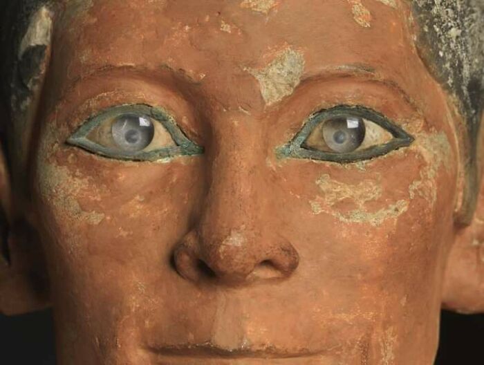Close-up of an ancient archeology find showing detailed eyes and worn terracotta face from a historical artifact.