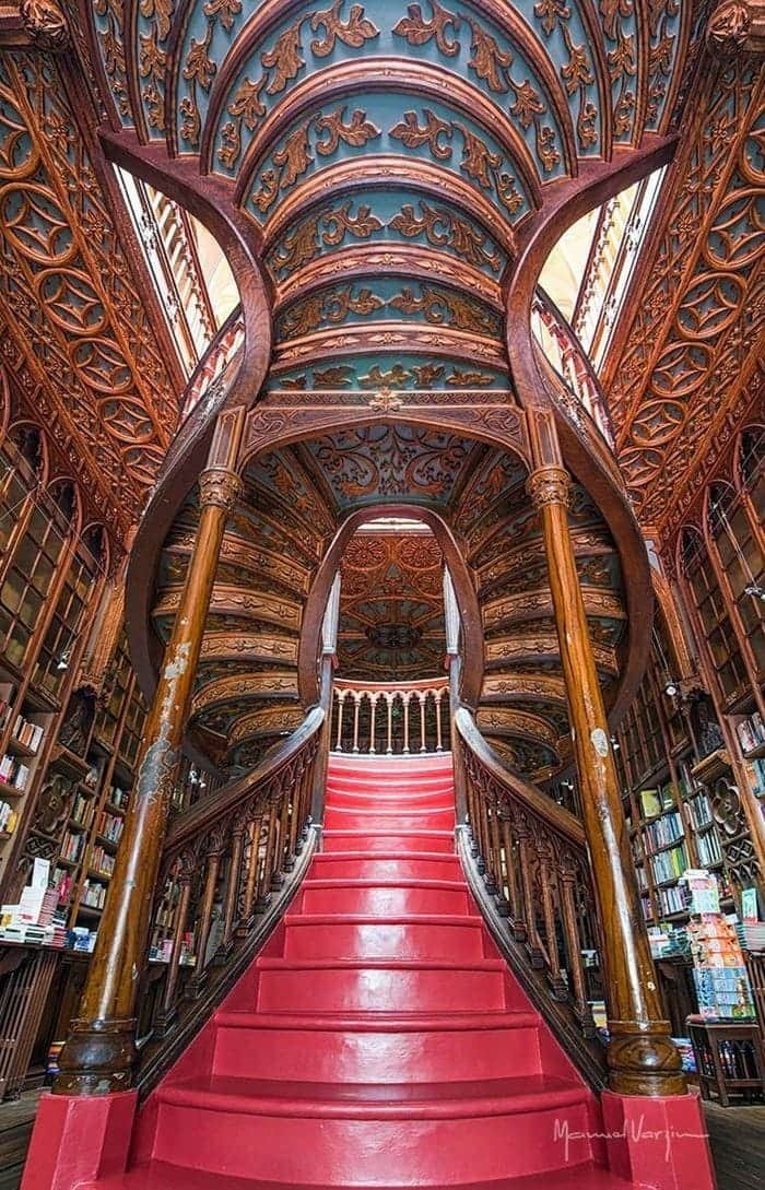 Ornate wooden staircase and detailed ceiling in a historic library, showcasing fascinating archeology-inspired architectural design.