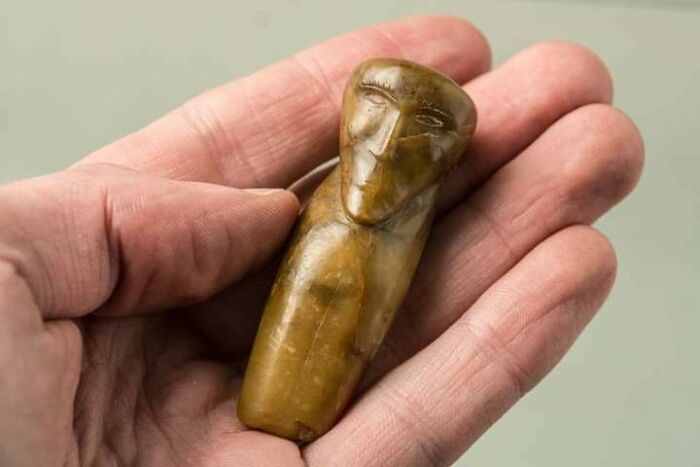 Hand holding a small ancient carved figurine, a fascinating archaeology find from around the world.