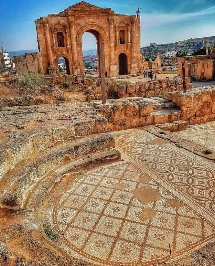 Ancient archaeological site with mosaic floor and stone archway, showcasing fascinating finds from around the world.